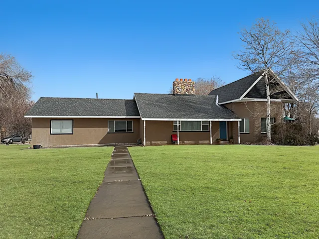 View of front of property with roof with shingles, a front lawn, stucco siding, and a chimney