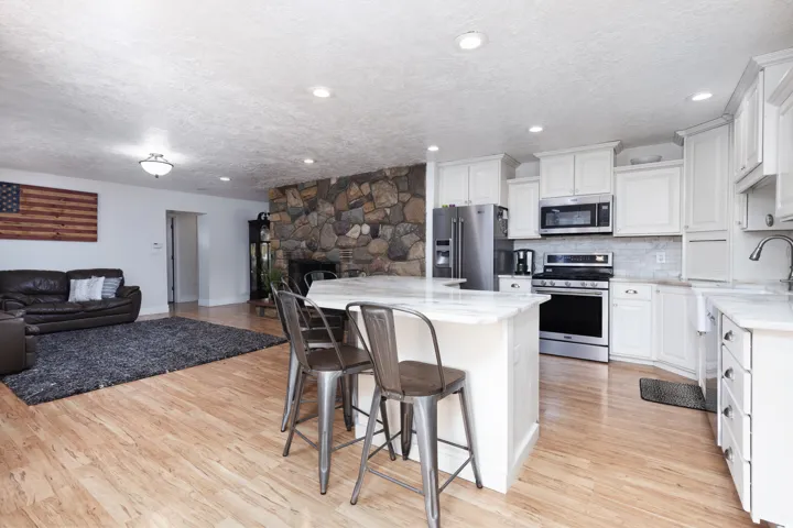 Kitchen featuring stainless steel appliances, a breakfast bar, white cabinets, open floor plan, and a textured ceiling