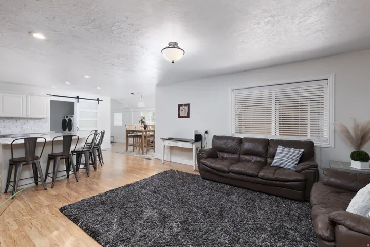 Living area featuring a textured ceiling, light wood finished floors, a barn door, and recessed lighting