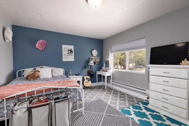 Bedroom with a baseboard heating unit, carpet, and an accent wall