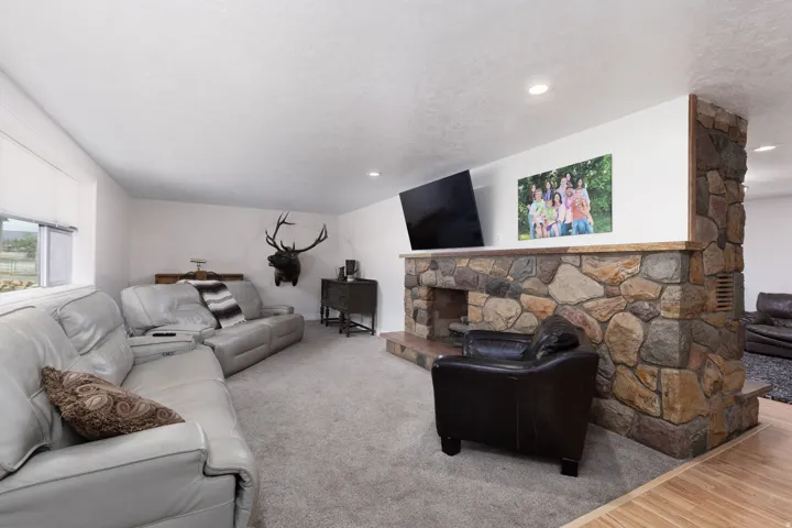 Living area with a stone fireplace and carpet flooring