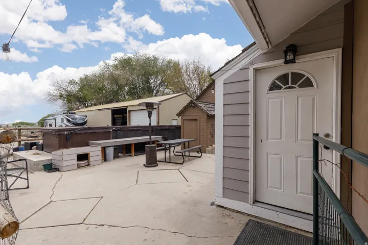 View of patio with a hot tub and a storage shed