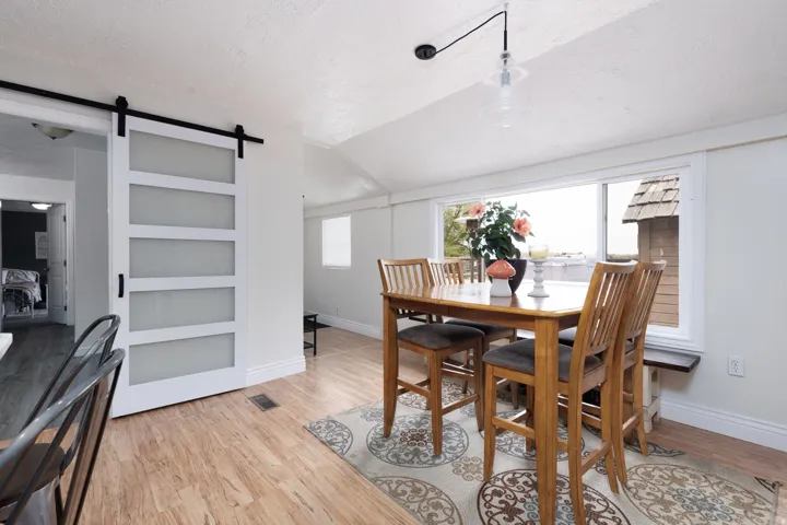 Dining space with a barn door, light wood finished floors, and built in shelves