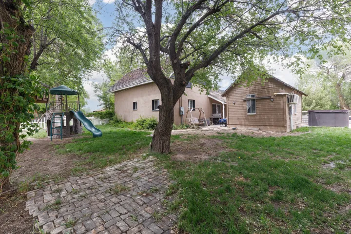 Rear view of property with a patio area, a playground, a lawn, and stucco siding