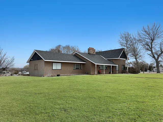 View of front of house with a front yard, a chimney, covered porch, and roof with shingles