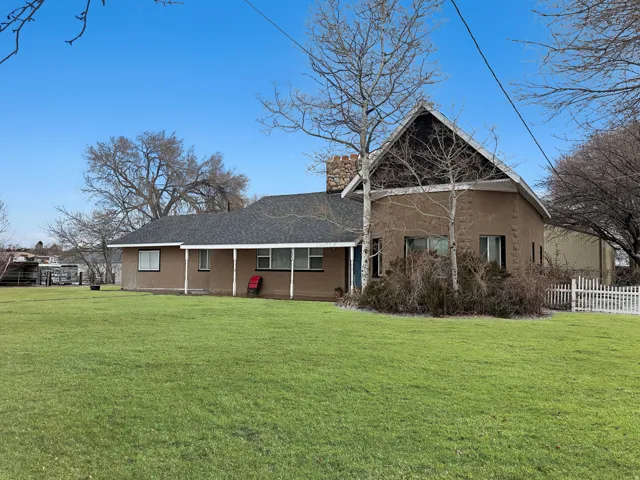 View of front of home with a shingled roof, stucco siding, a chimney, and a porch