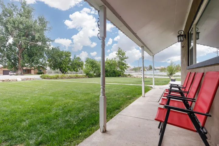 View of green lawn featuring covered porch