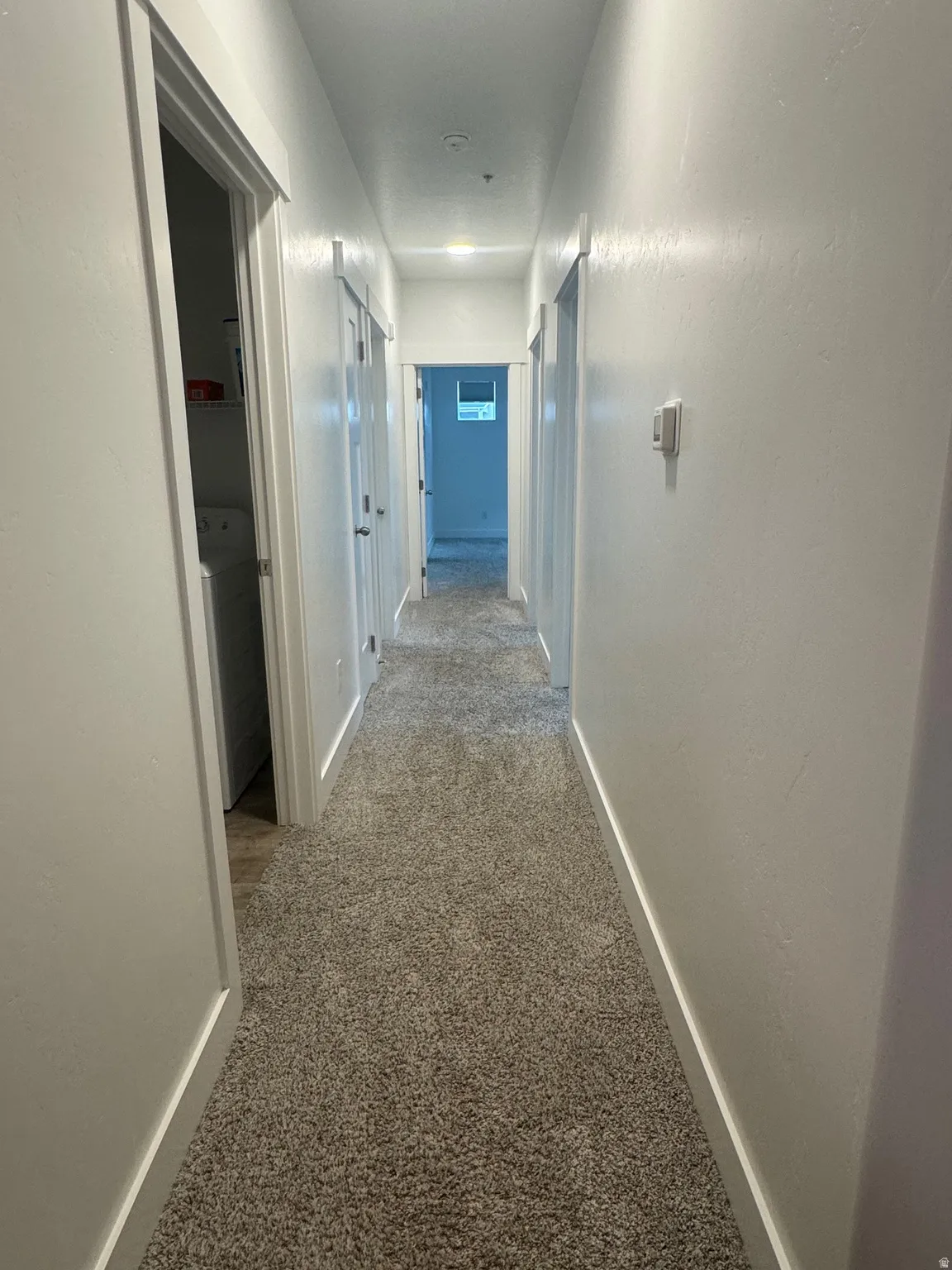 Hall featuring light colored carpet and washer / clothes dryer