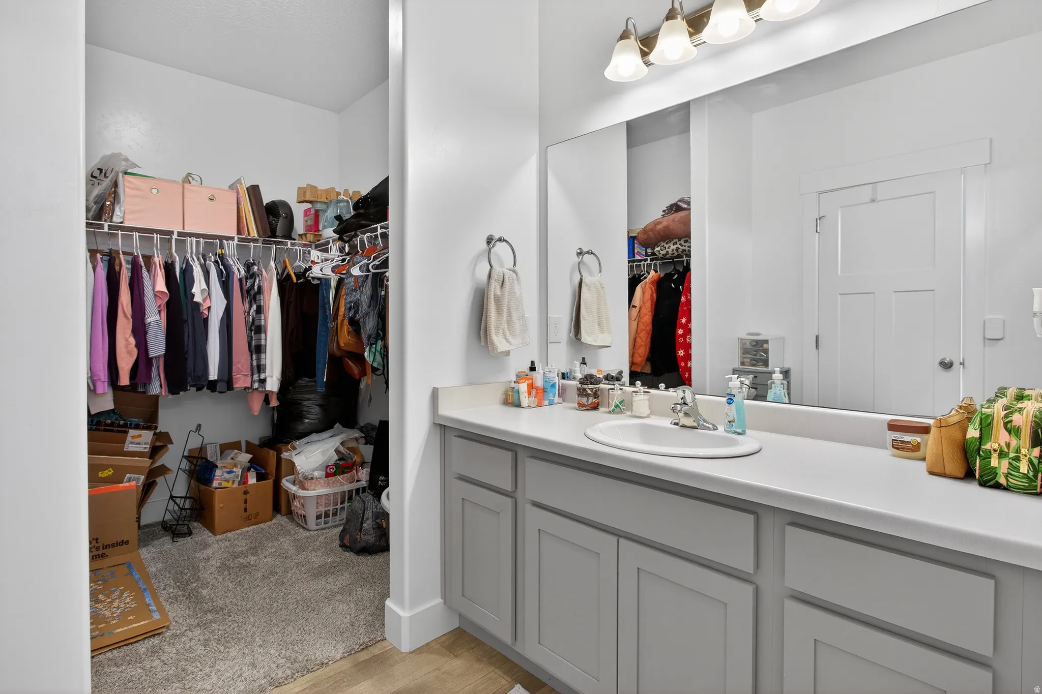 Full bathroom with a spacious closet, vanity, and light wood finished floors
