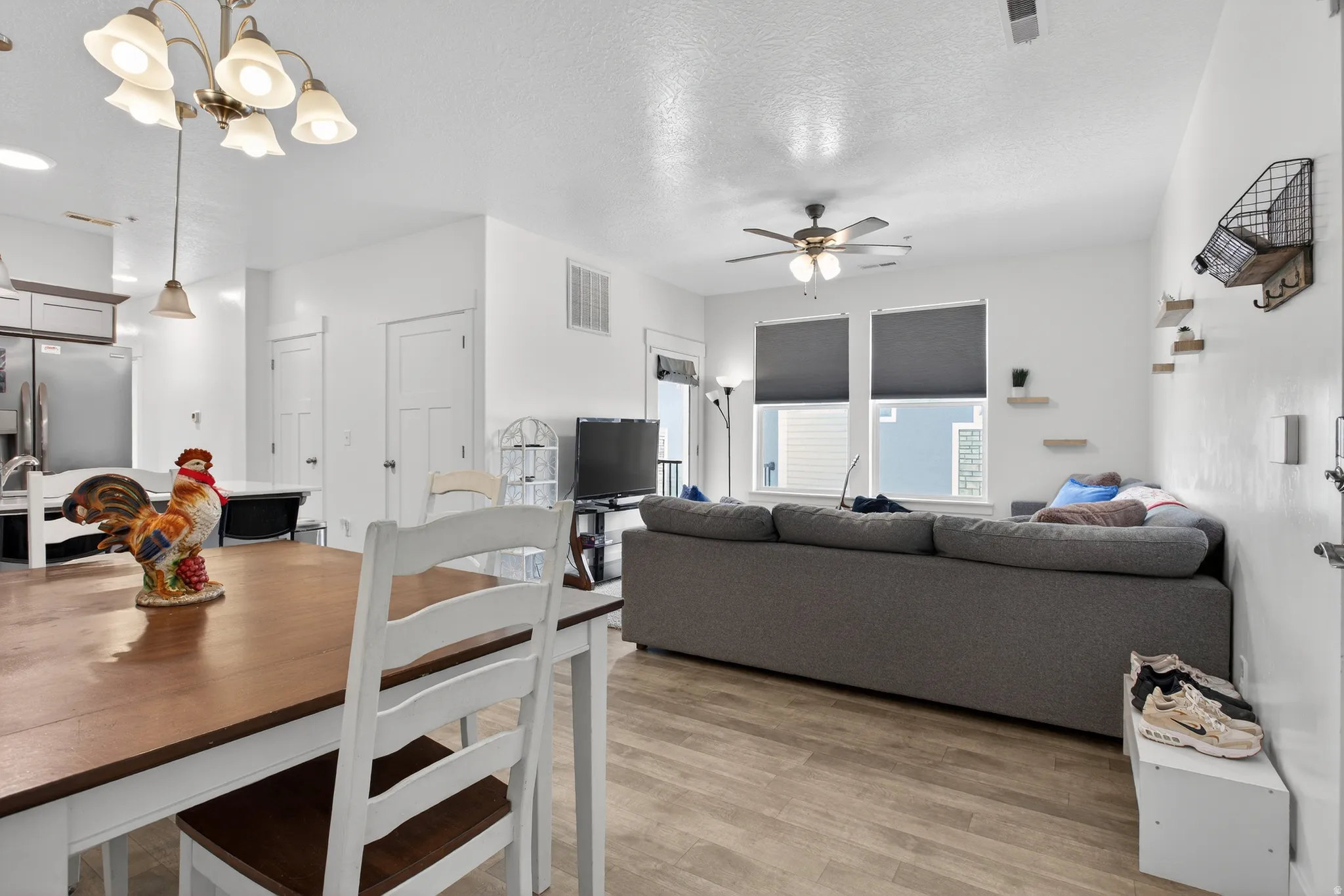 Dining space featuring light wood-style floors, ceiling fan, a textured ceiling, and hanging lights