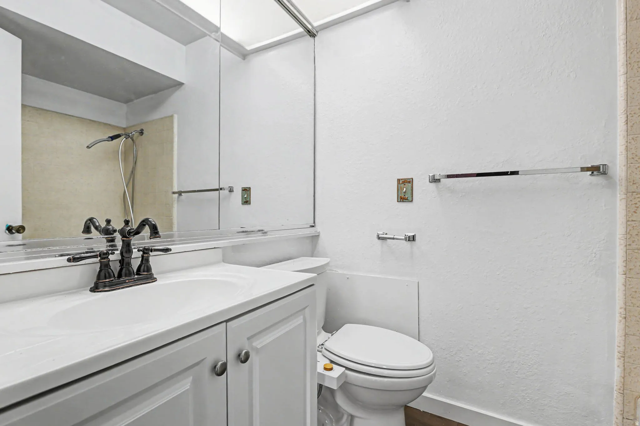 Full bath with vanity, a textured wall, and a shower