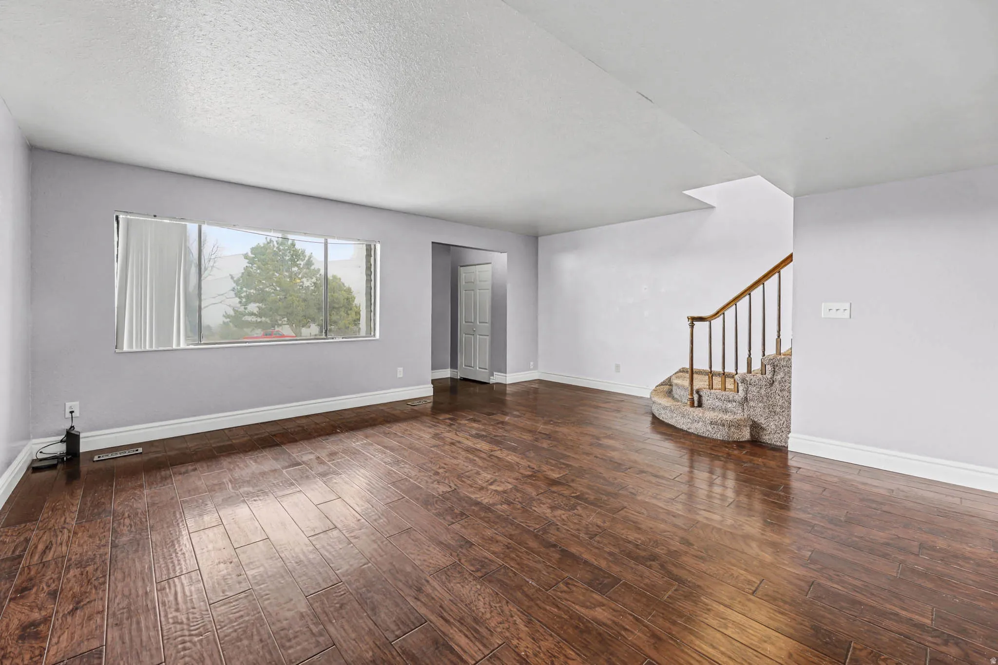Unfurnished living room with dark wood finished floors and a textured ceiling