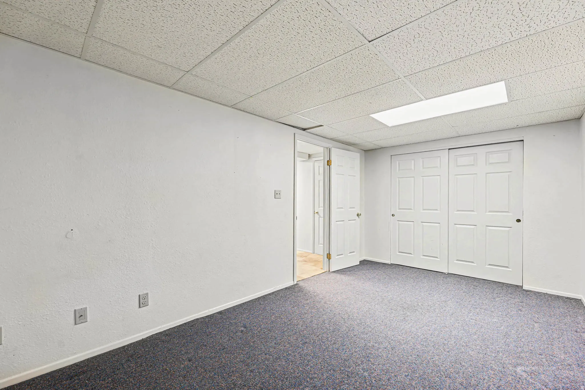 Finished basement with a drop ceiling and carpet floors