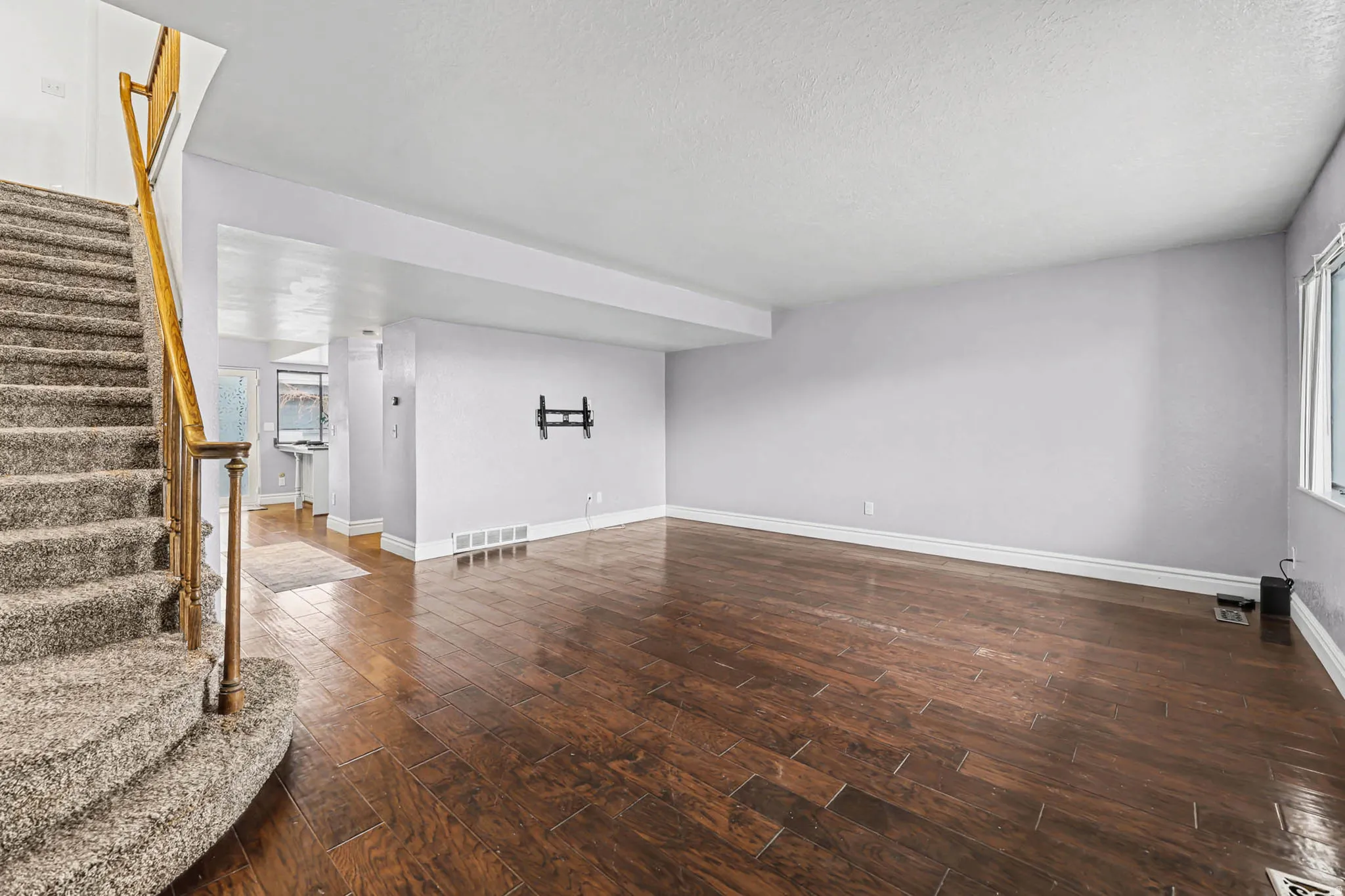 Unfurnished living room featuring dark wood-style floors and plenty of natural light