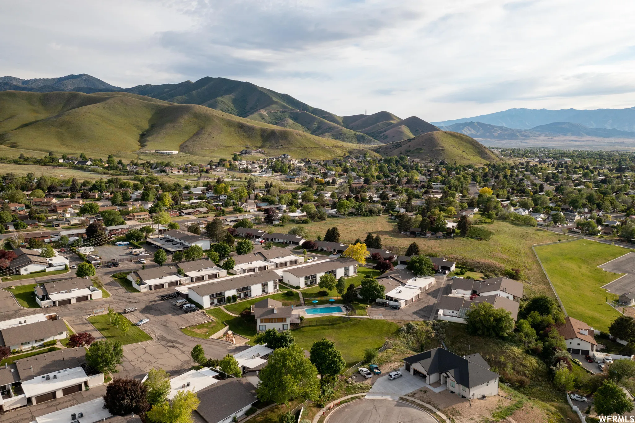 Aerial perspective of suburban area featuring a mountainous background and a pool