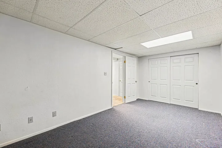 Finished basement with a drop ceiling and carpet floors