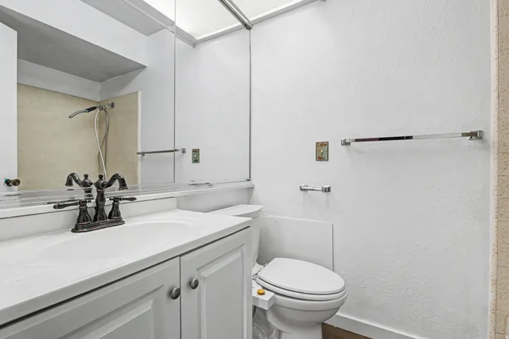 Full bath with vanity, a textured wall, and a shower
