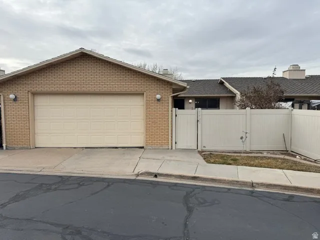 Ranch-style house featuring a gate, driveway, brick siding, and an attached garage