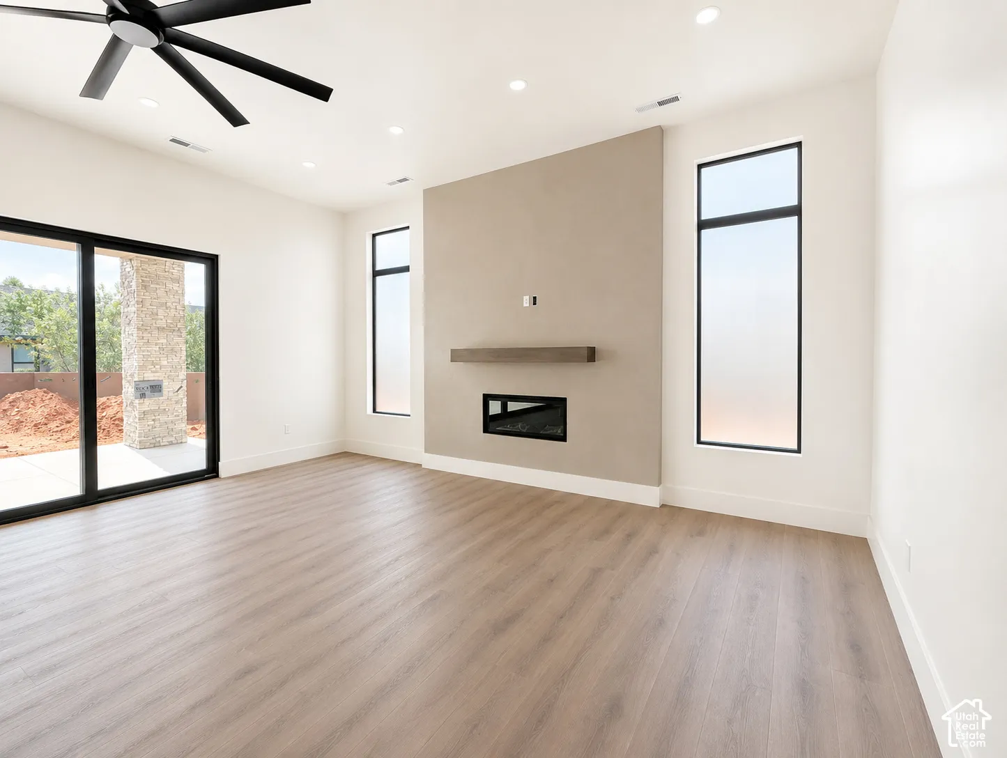 Spacious room featuring wood-finish flooring, a built-in electric fireplace, a floating mantel, and recessed lighting