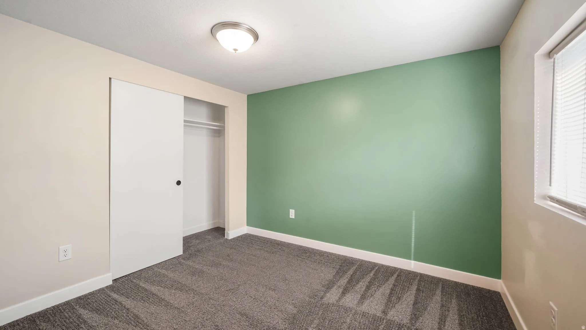 Unfurnished bedroom featuring a closet and dark colored carpet