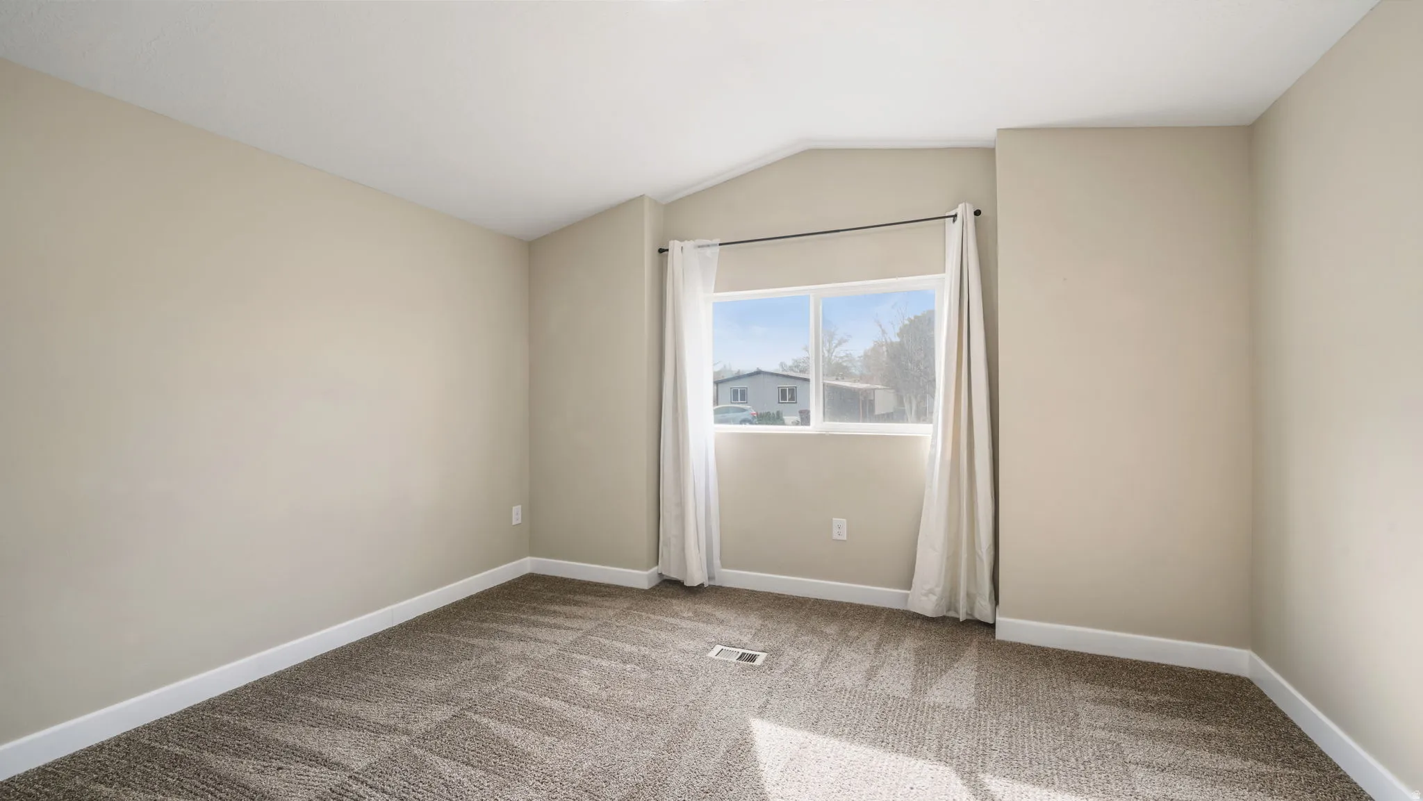 Spare room featuring lofted ceiling and light carpet