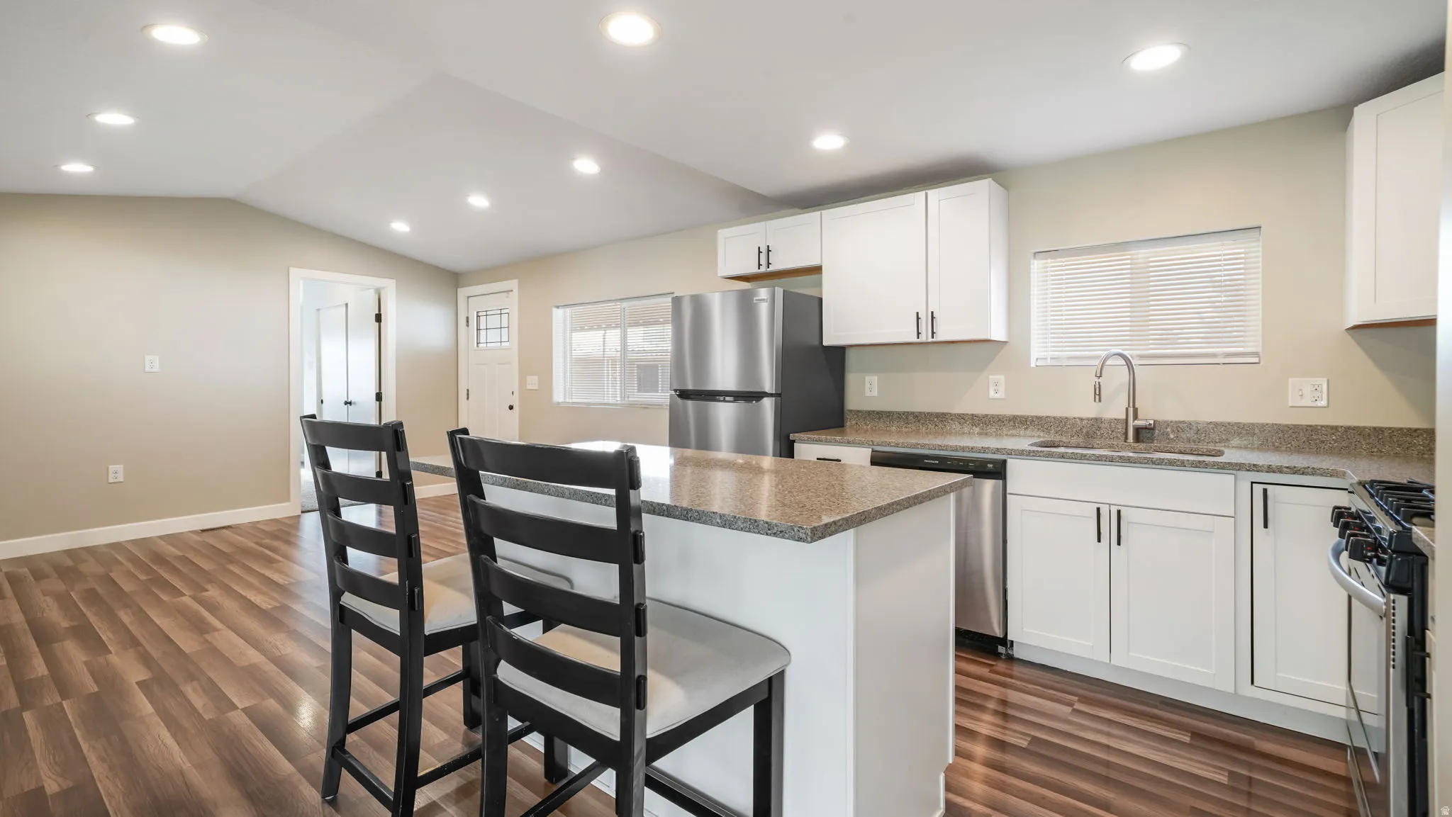 Kitchen with a kitchen breakfast bar, stainless steel appliances, white cabinetry, a center island, and recessed lighting