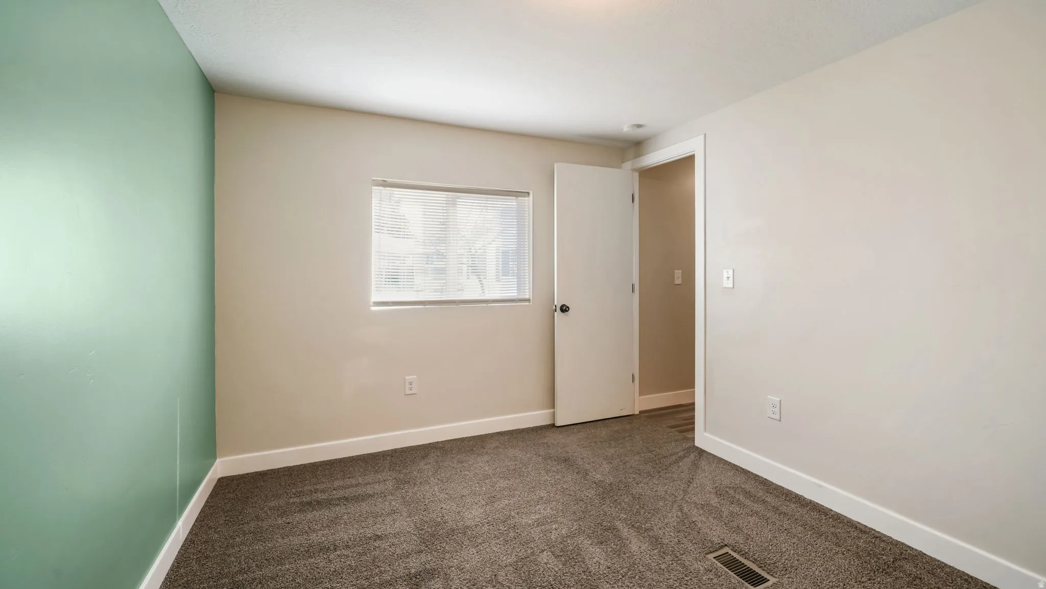 Carpeted spare room with baseboards