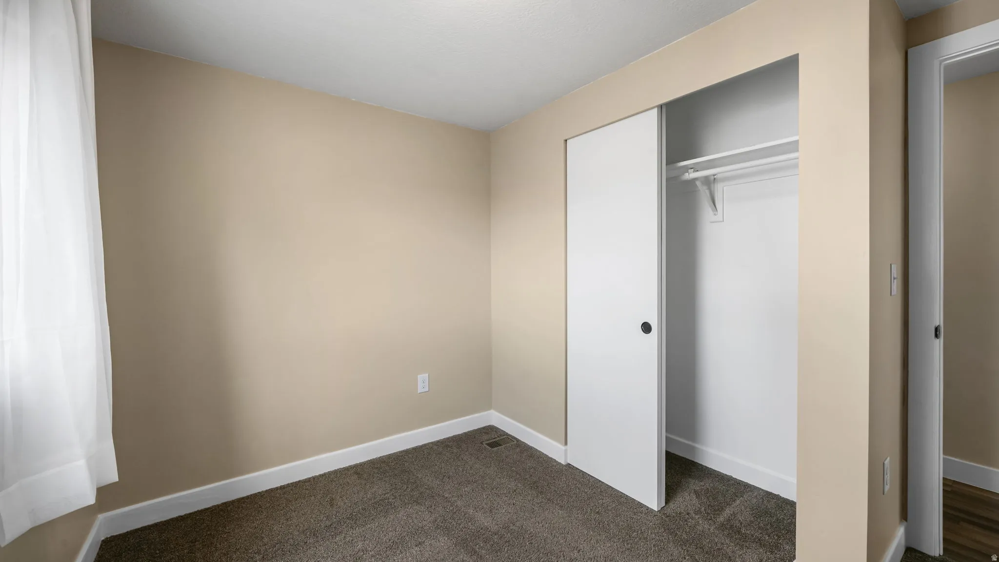 Unfurnished bedroom featuring dark colored carpet and a closet