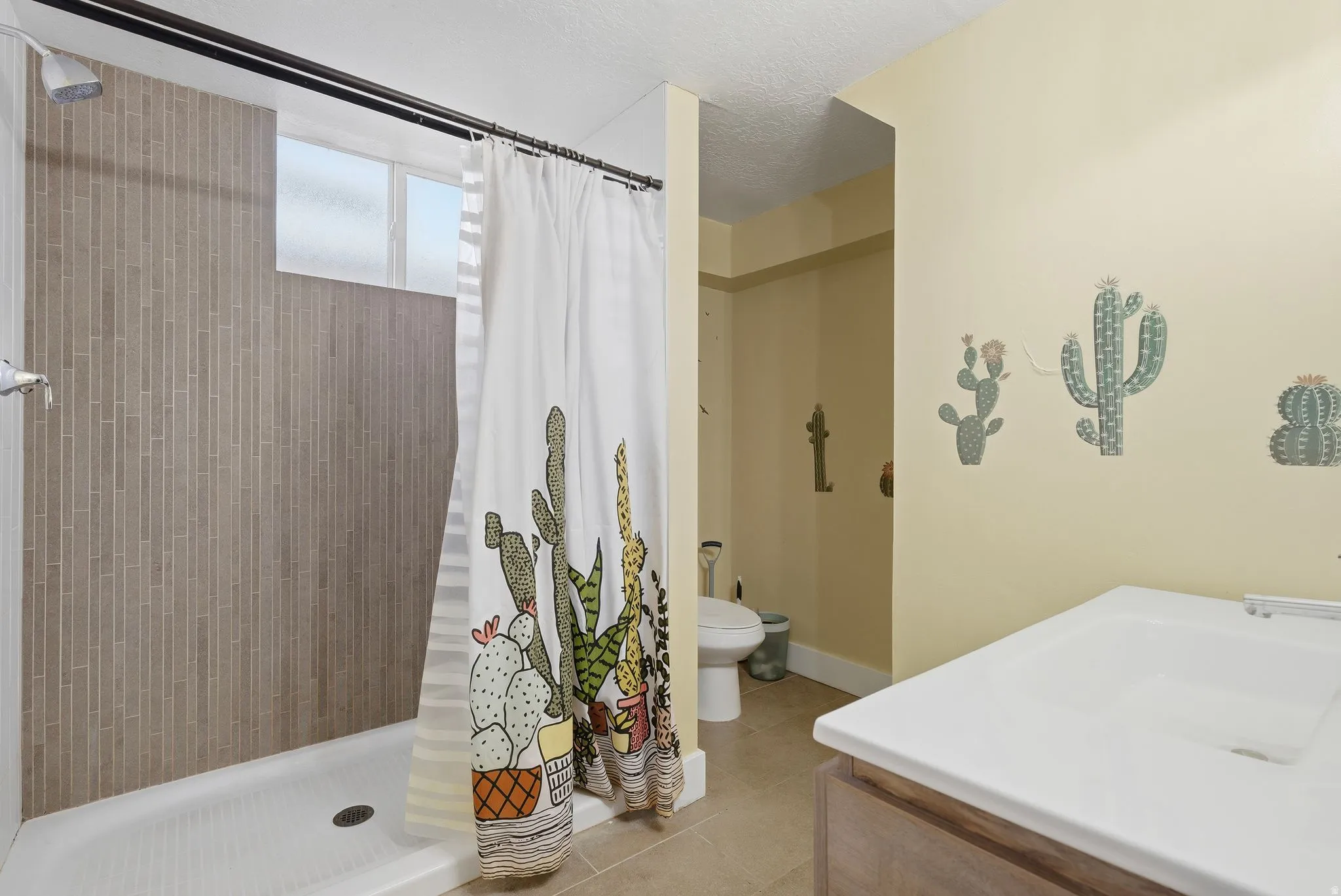 Full bath with a shower stall, light tile patterned floors, and vanity