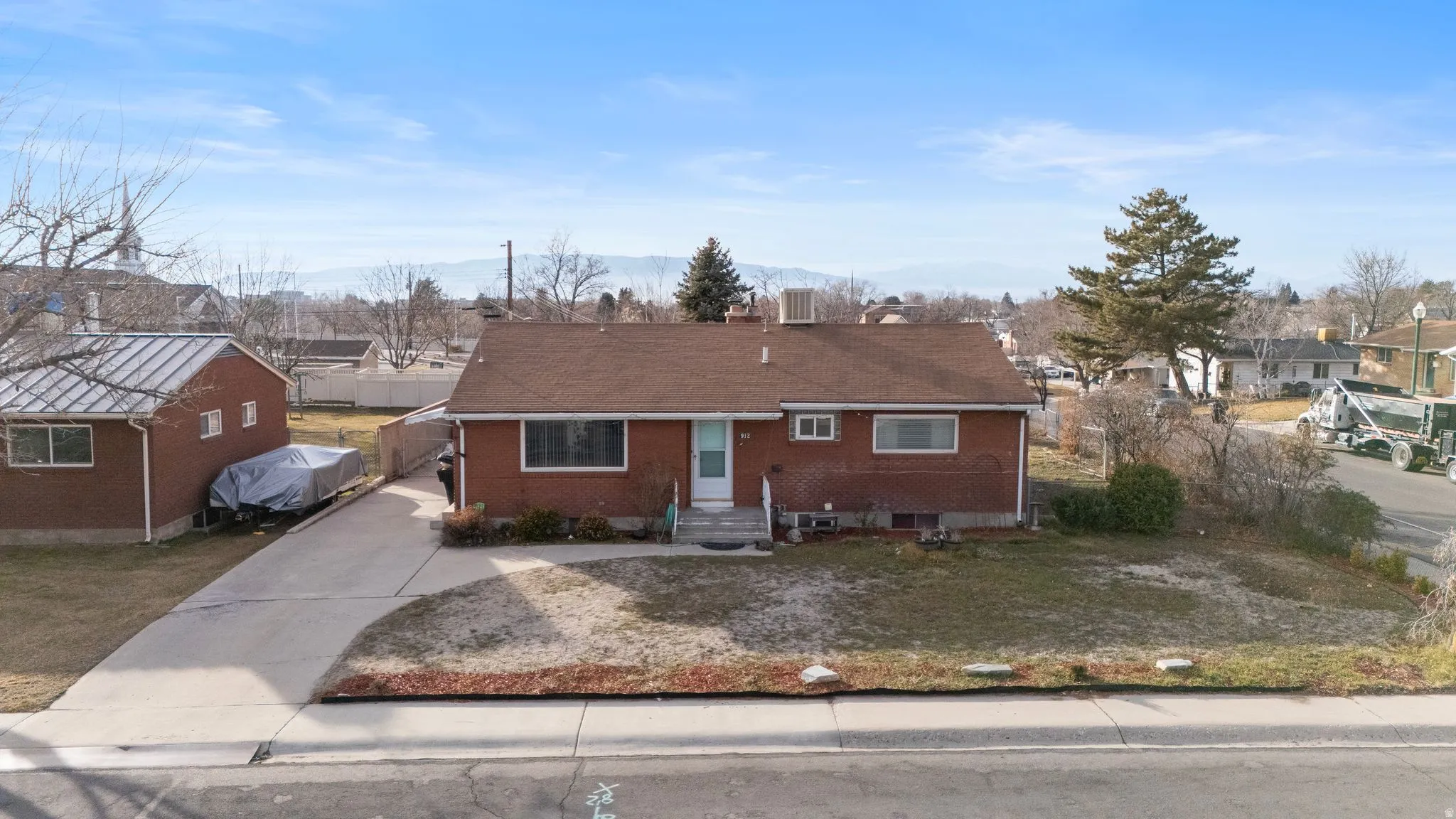 View of front of home with driveway, brick siding, a chimney, and a residential view