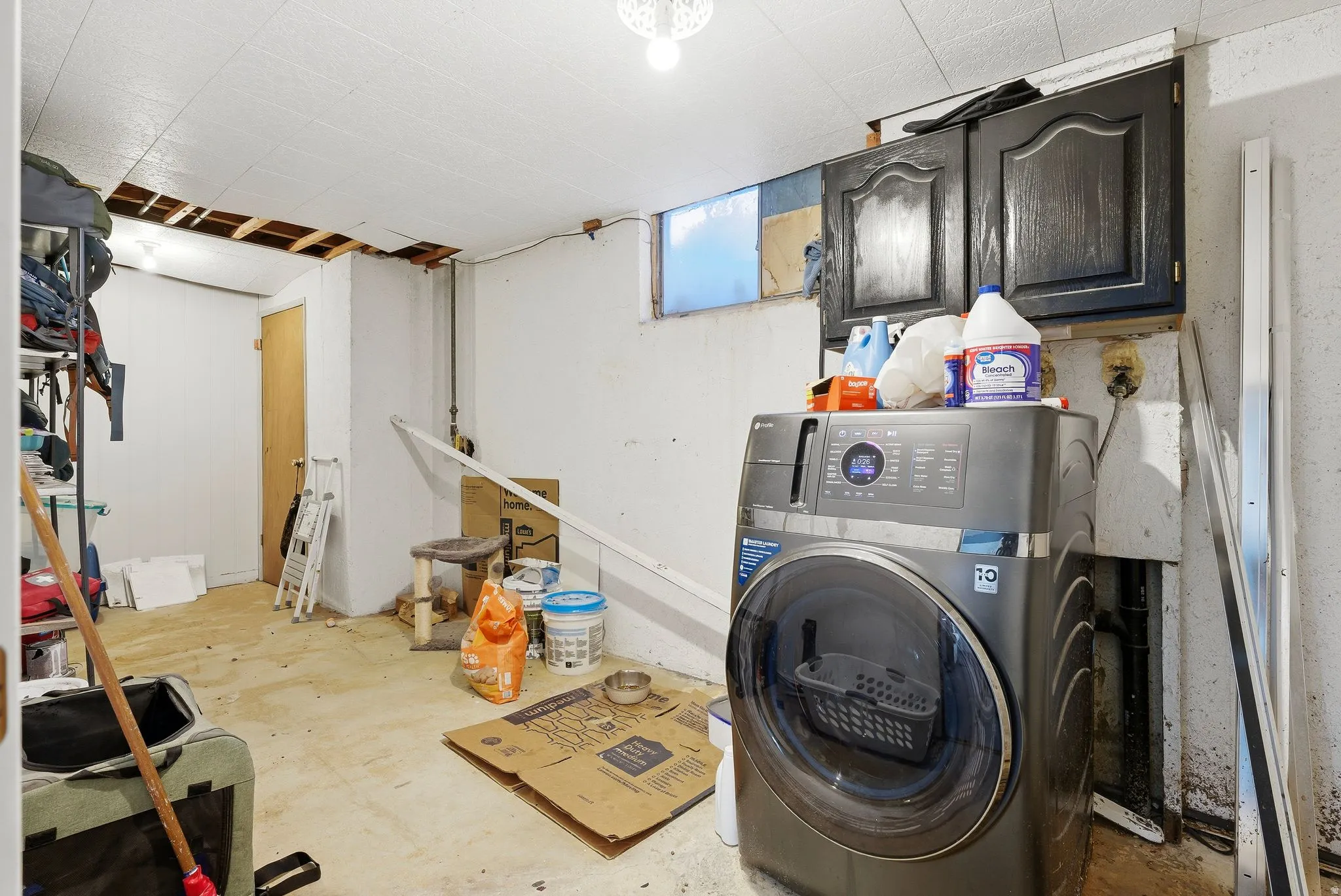 Laundry room featuring washer / clothes dryer, unfinished concrete flooring, and cabinet space