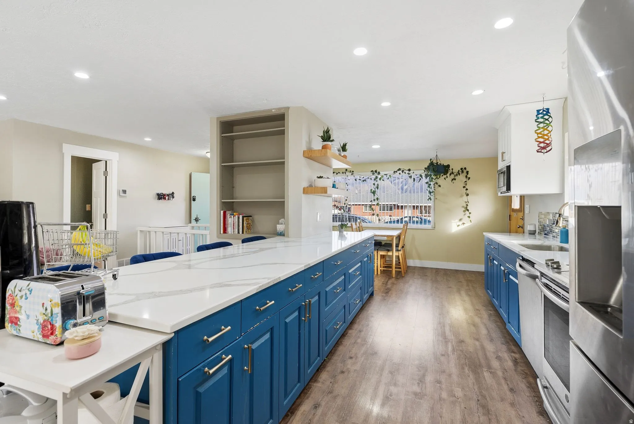 Dual tone kitchen with dual tone cabinetry, stainless steel appliances, dark wood-style flooring, light stone counters, and open shelves