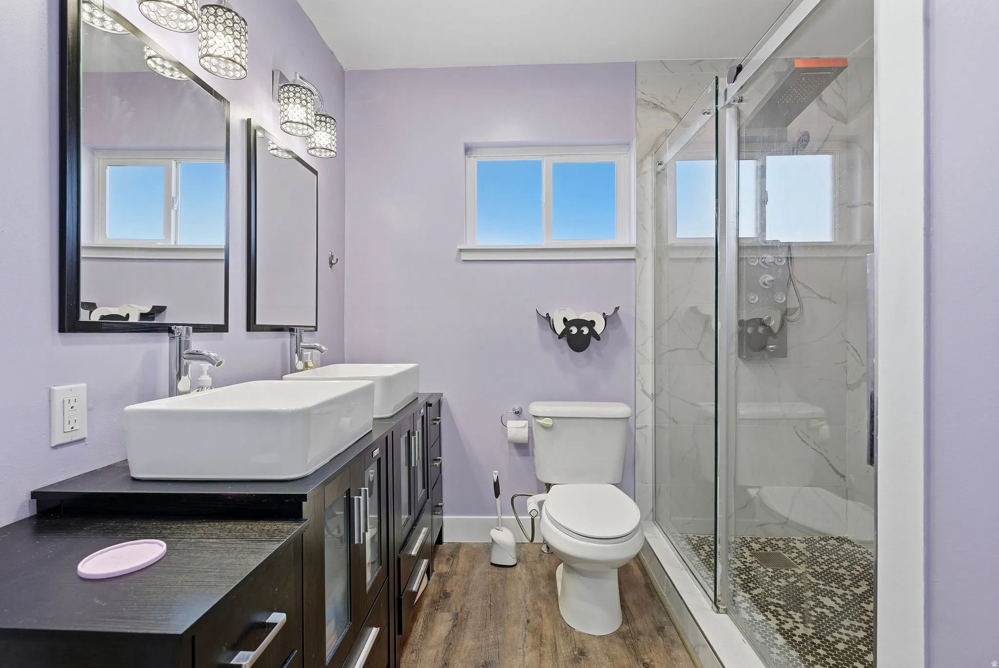 Full bath featuring double vanity, a marble finish shower, and wood finished floors