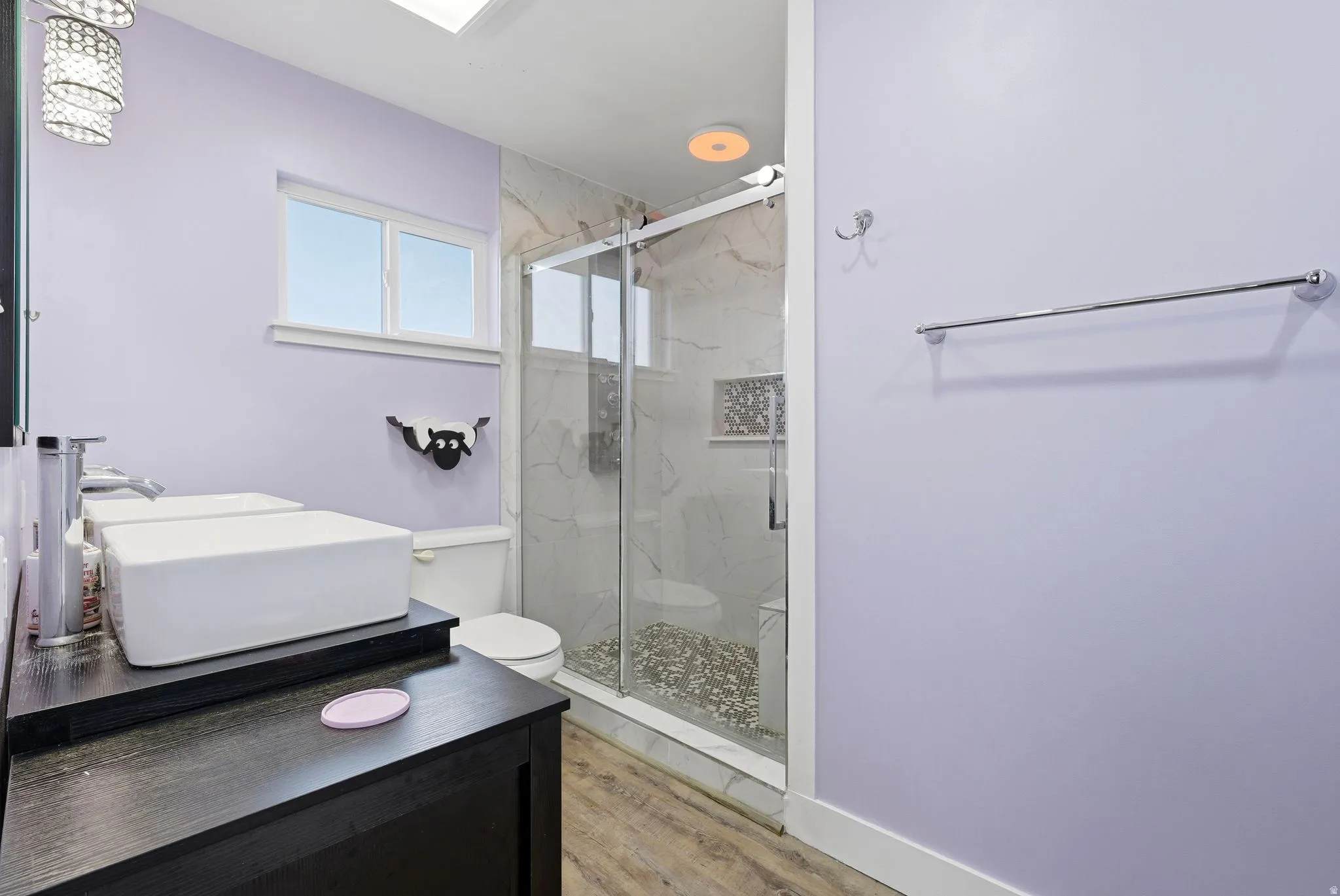Full bath with a marble finish shower, vanity, and light wood-type flooring