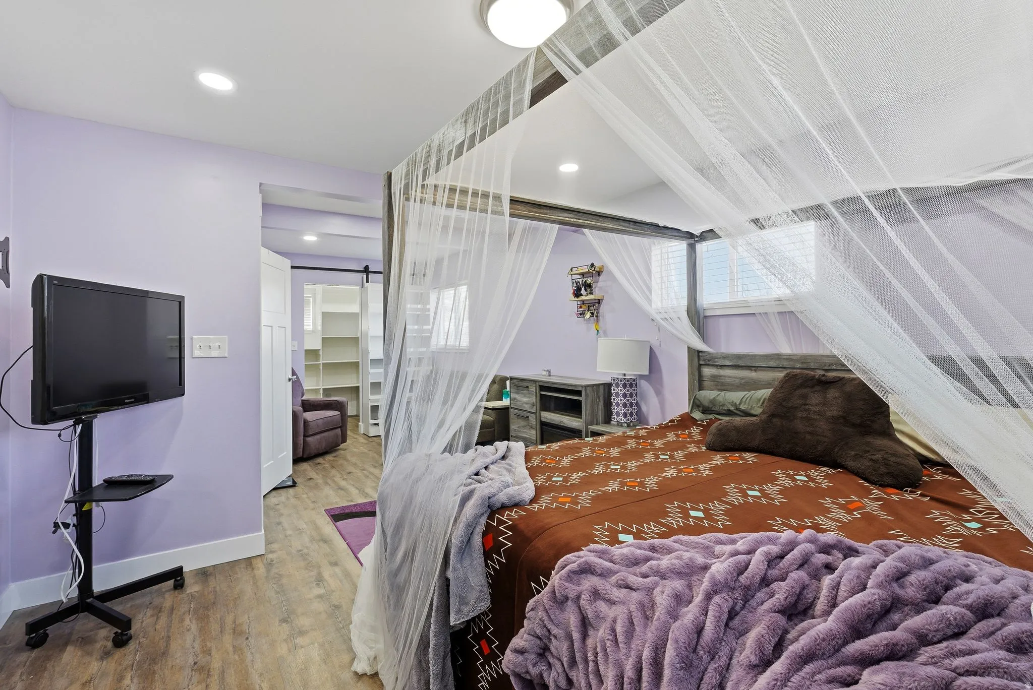 Bedroom with a walk in closet, wood finished floors, a barn door, and recessed lighting