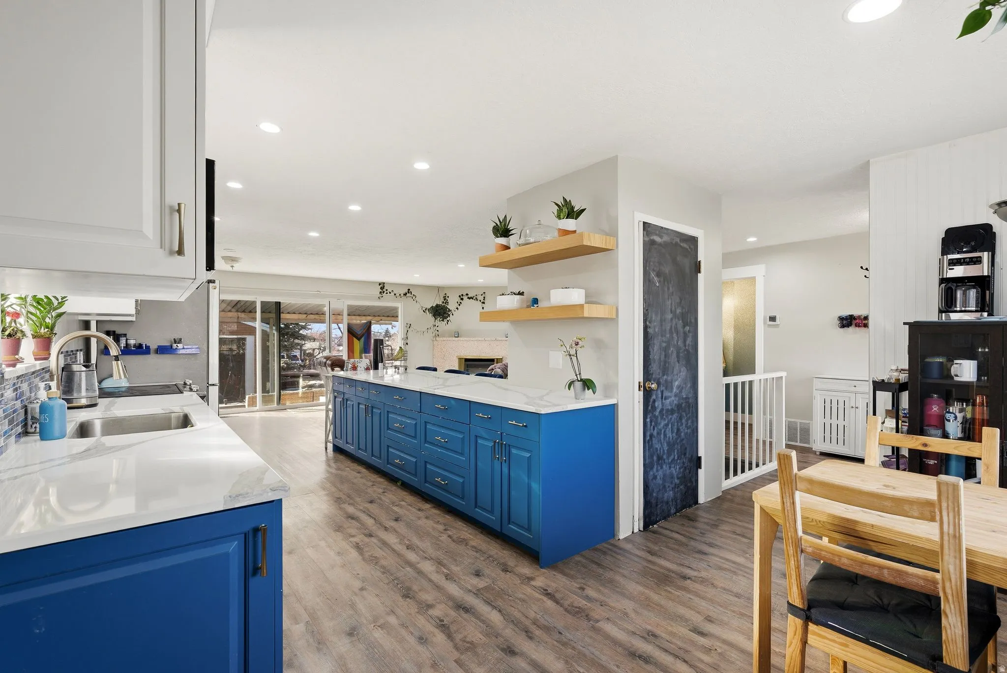 Two tone kitchen with light wood-type flooring, open shelves, light stone counters, dual tone cabinets, and recessed lighting