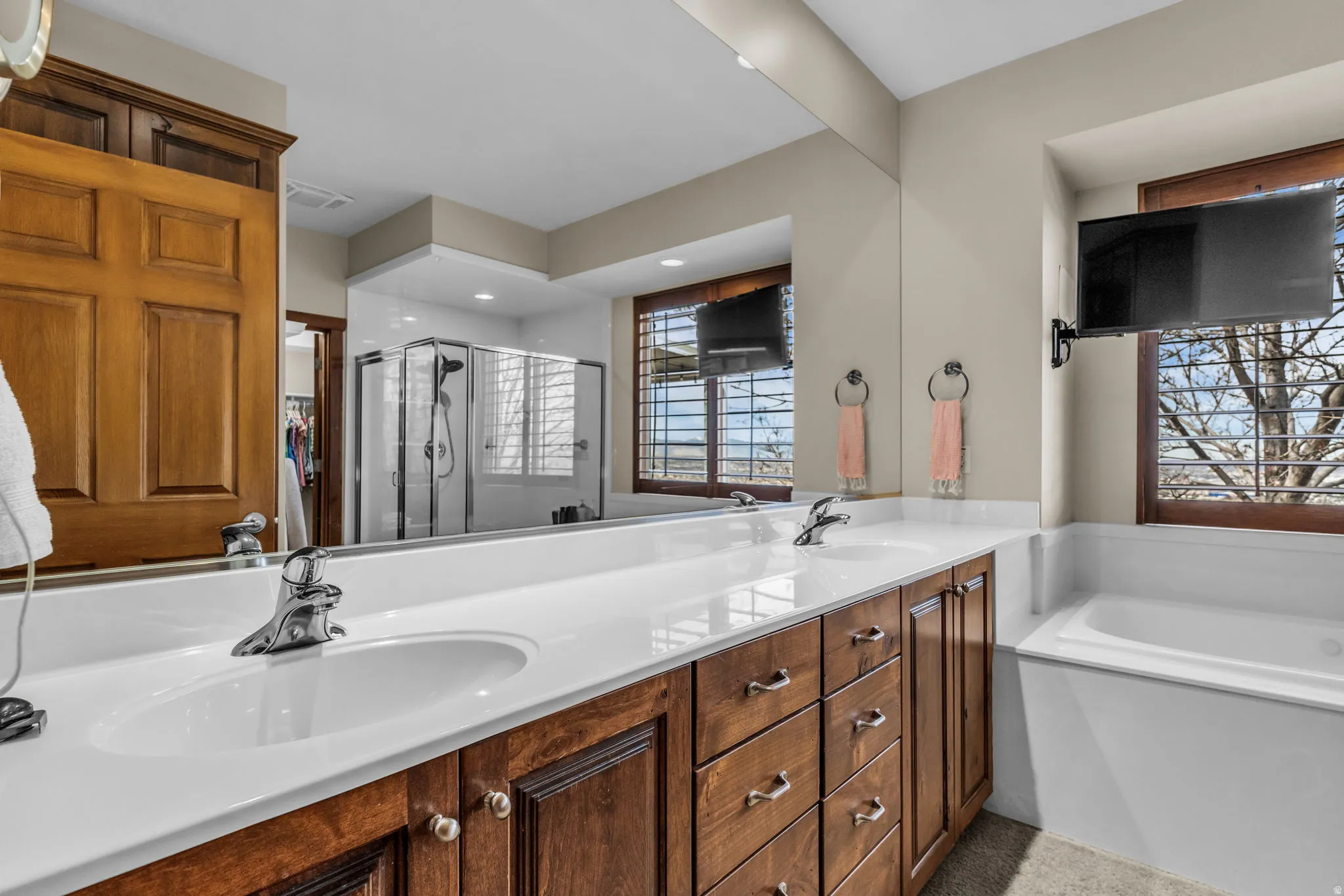 Bathroom featuring double vanity, a shower stall, a garden tub, and a walk in closet