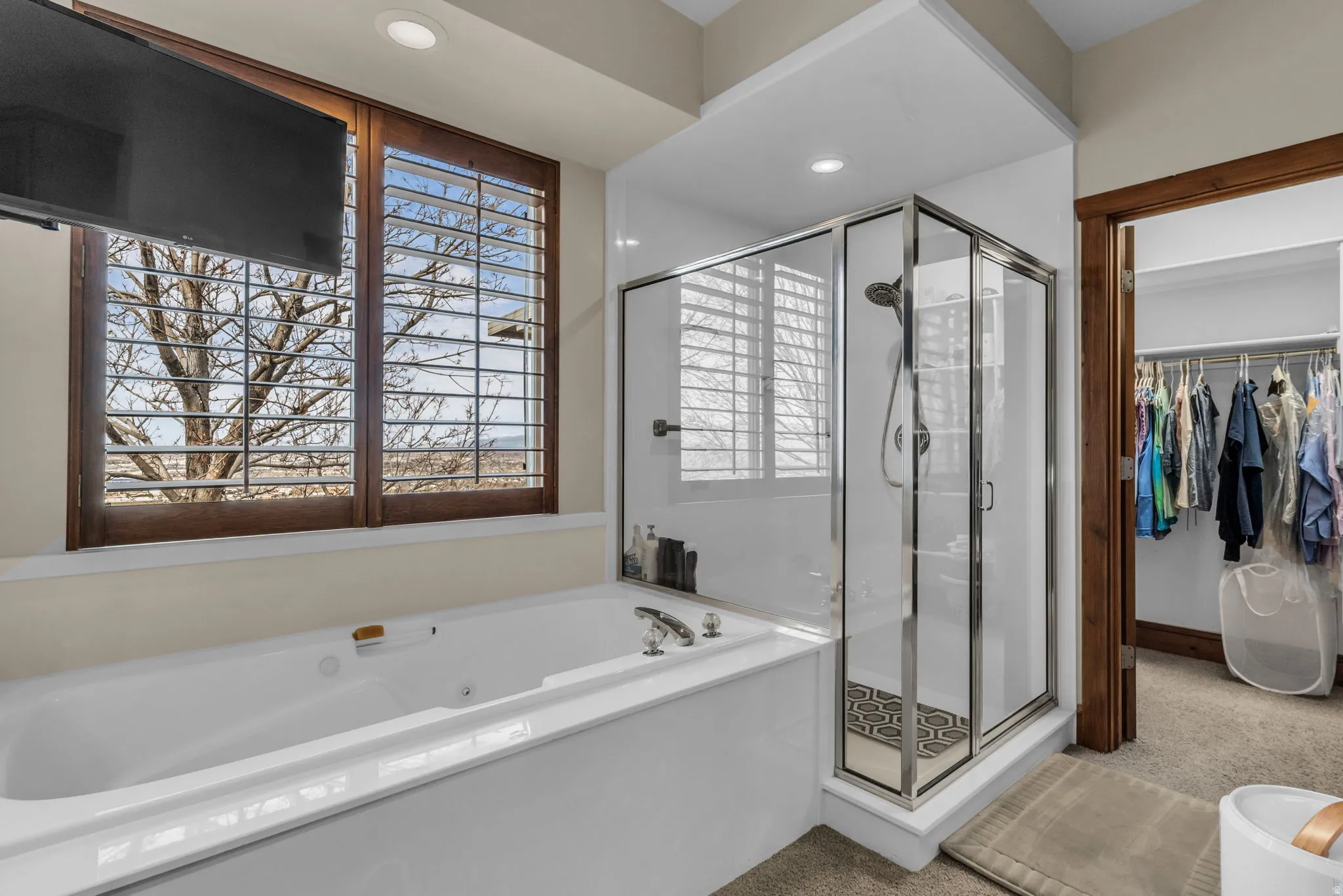 Bathroom featuring a whirlpool tub, a stall shower, a spacious closet, and recessed lighting