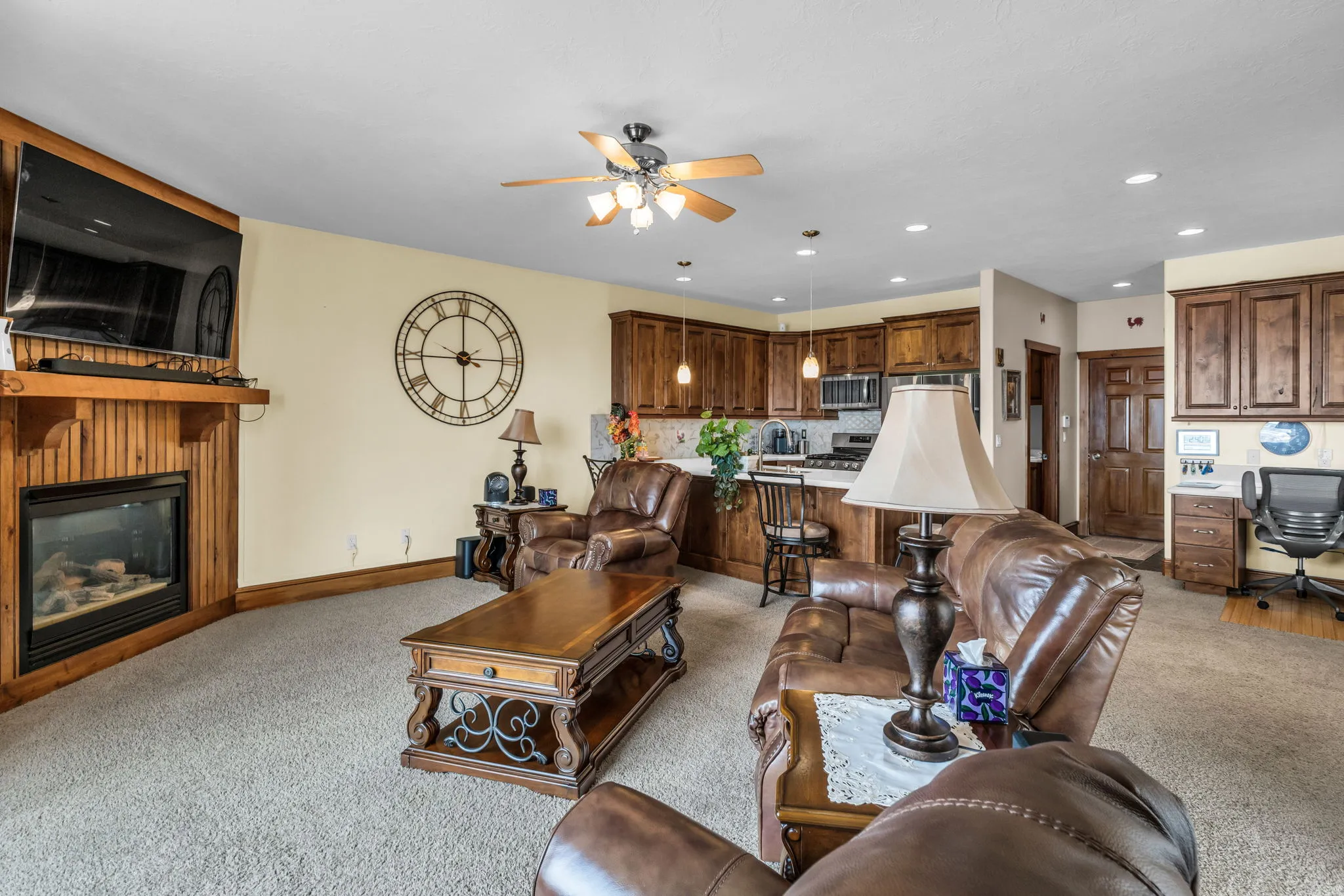 Living room featuring ceiling fan, a glass covered fireplace, light carpet, recessed lighting, and an office area