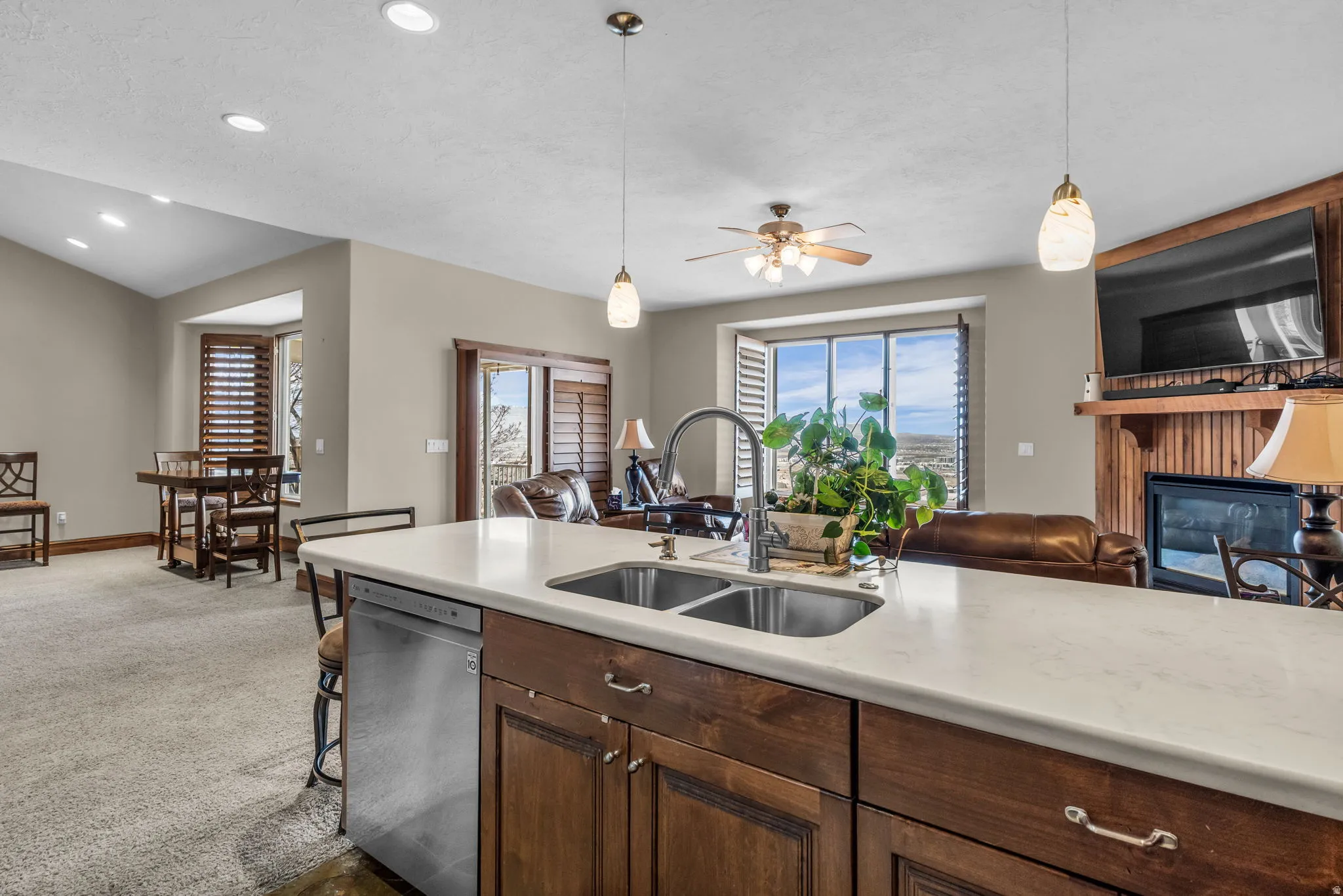 Kitchen with stainless steel dishwasher, a fireplace, pendant lighting, and open floor plan