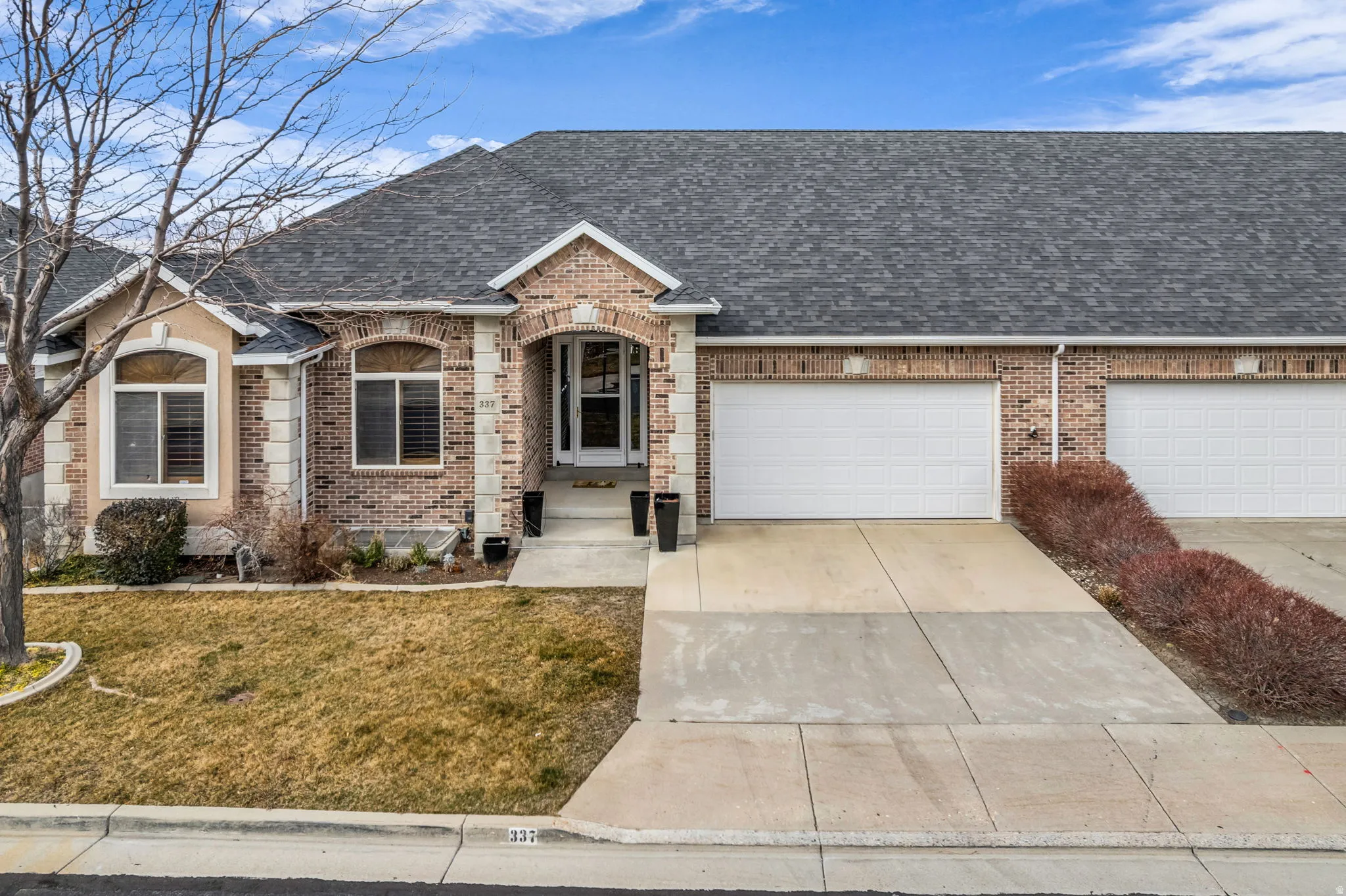 French country style house featuring roof with shingles, brick siding, and concrete driveway