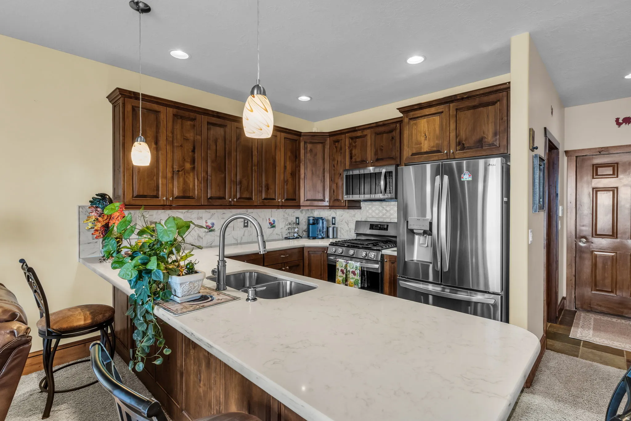 Kitchen featuring stainless steel appliances, a breakfast bar, a peninsula, backsplash, and pendant lighting