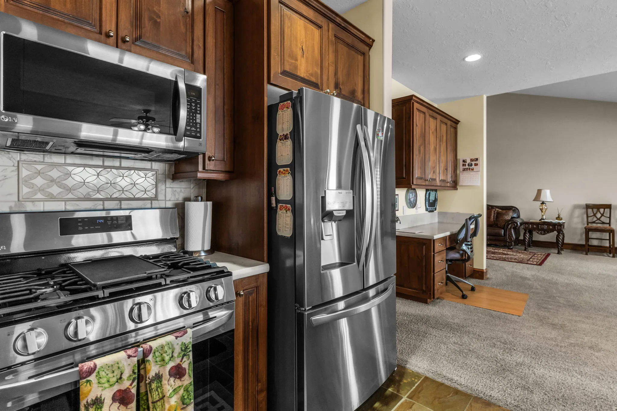 Kitchen with stainless steel appliances, light countertops, dark carpet, a textured ceiling, and recessed lighting