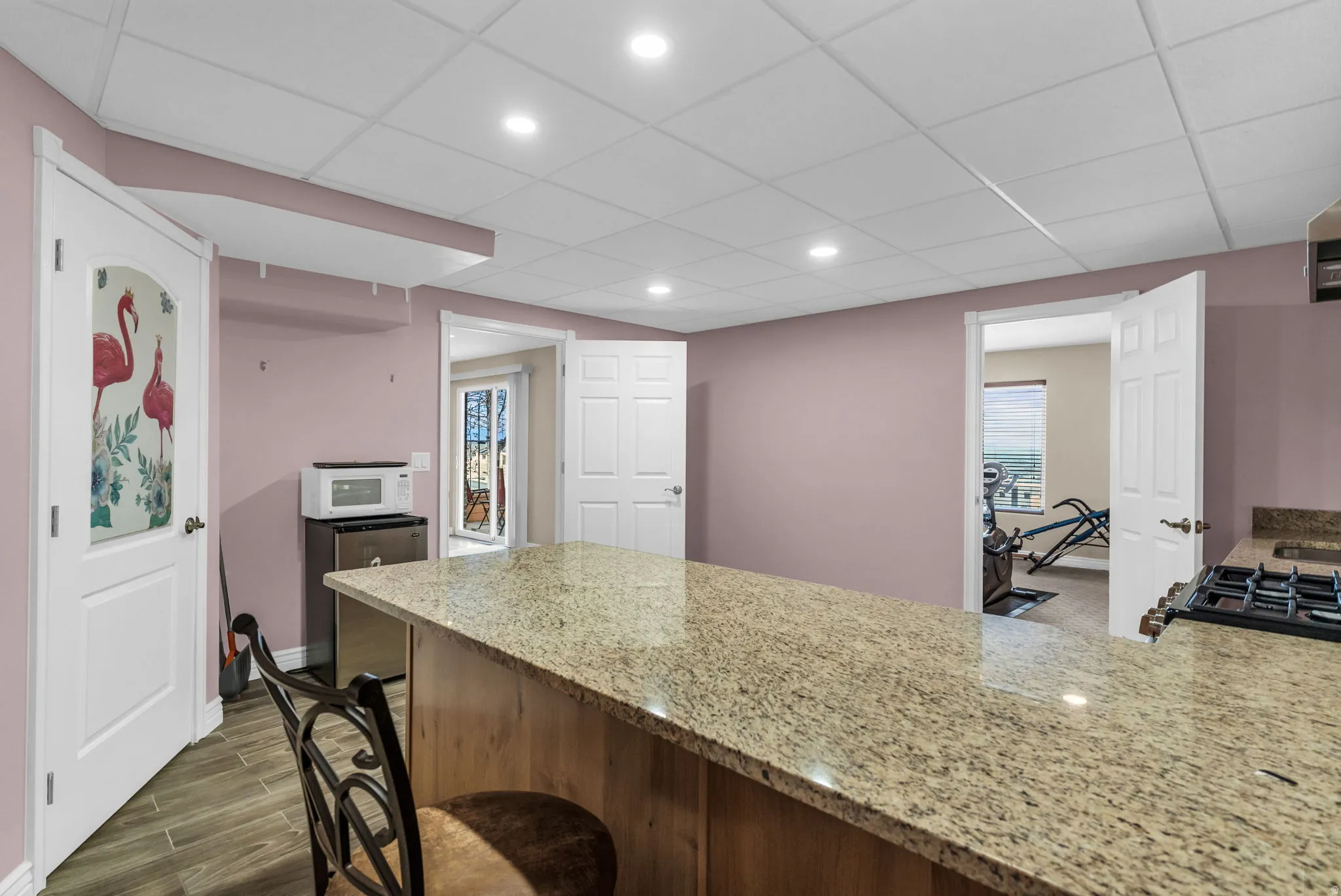 Kitchen with light stone counters, a peninsula, a paneled ceiling, wood finish floors, and recessed lighting