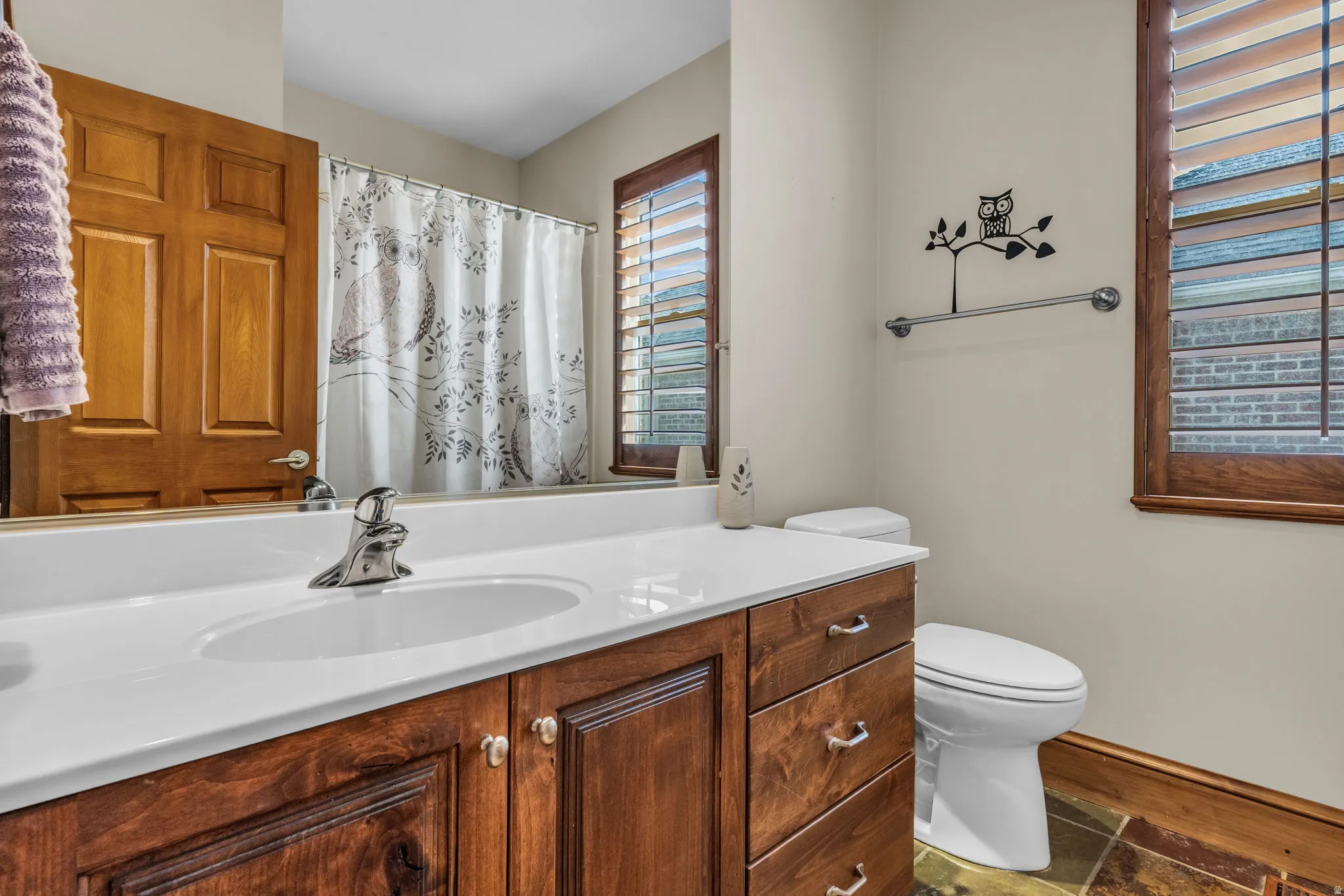 Full bathroom with vanity, a shower with curtain, and dark stone finish floors
