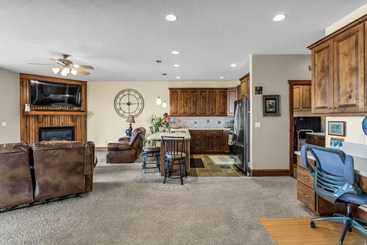 Living area featuring a glass covered fireplace, a ceiling fan, recessed lighting, and light carpet