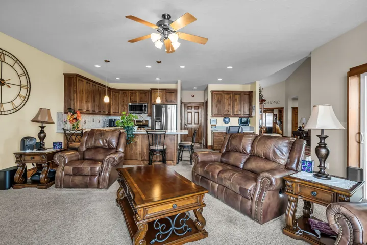 Living area with a ceiling fan, light colored carpet, and recessed lighting