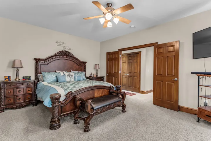 Bedroom with light colored carpet and a ceiling fan