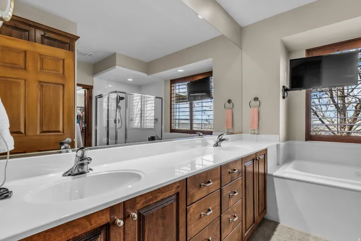 Bathroom featuring double vanity, a shower stall, a garden tub, and a walk in closet
