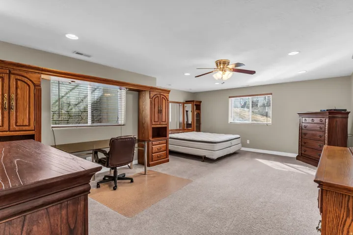 Bedroom with light colored carpet, ceiling fan, recessed lighting, and an office area
